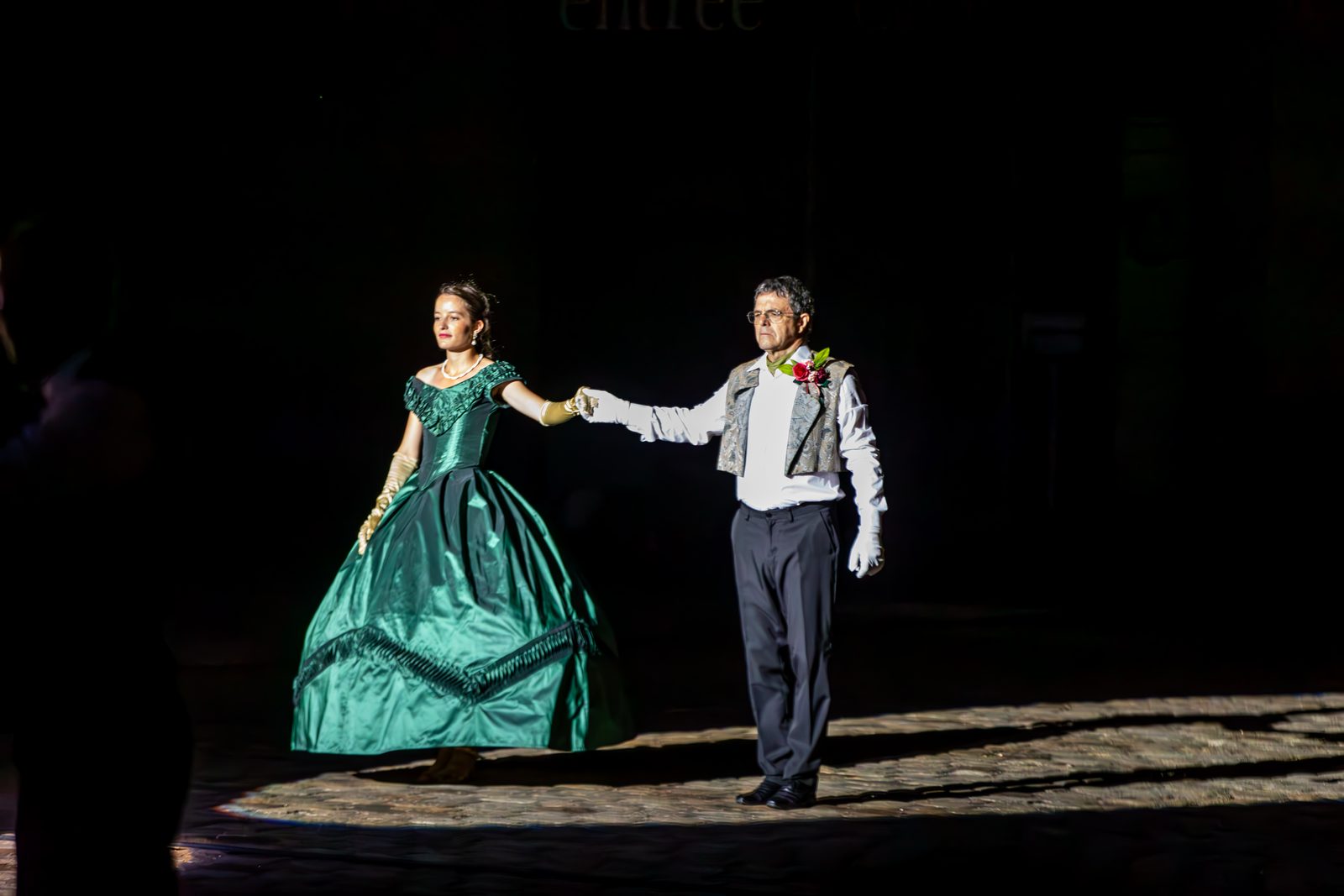Une danseuse en robe verte de soie et son cavalier, dans un cercle de lumière