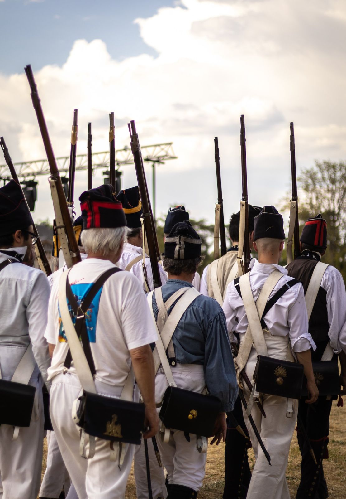 Des figurants en uniforme blanc, fusil à l’épaule, vus de dos
