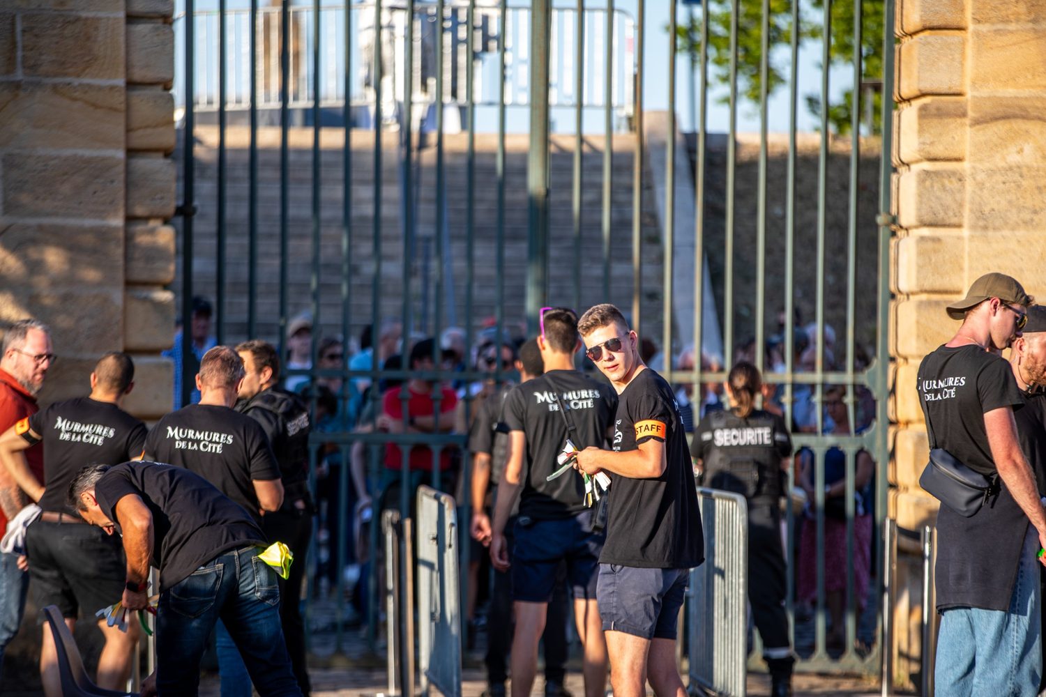 L’équipe de bénévoles en tee-shirt Murmures de la Cité accueille le public derrière une grille