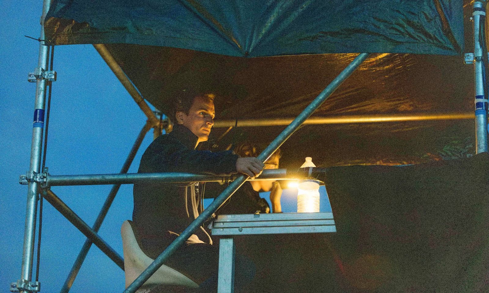Un technicien à la régie, sous une bâche, à la tombée de la nuit